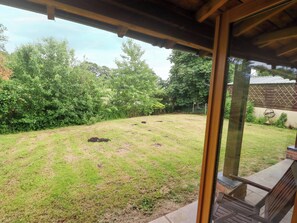 A covered patio area with a view of a grassy yard and trees.