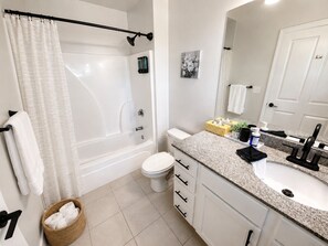 A modern bathroom with a shower, toilet, and sink. - Executive 3BR Downtown Birmingham with Game Table (Birmingham)