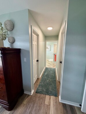 A hallway with a wooden floor, a green rug, and a wooden dresser. - Your Sebring Escape 3BR Home with Private Pool (Sebring)