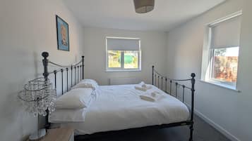 A bedroom with a bed, a radiator, a window, and a picture on the wall.