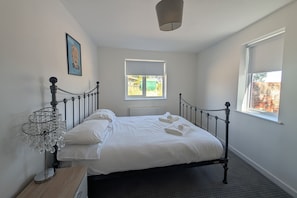 A bedroom with a bed, a radiator, a window, and a picture on the wall.