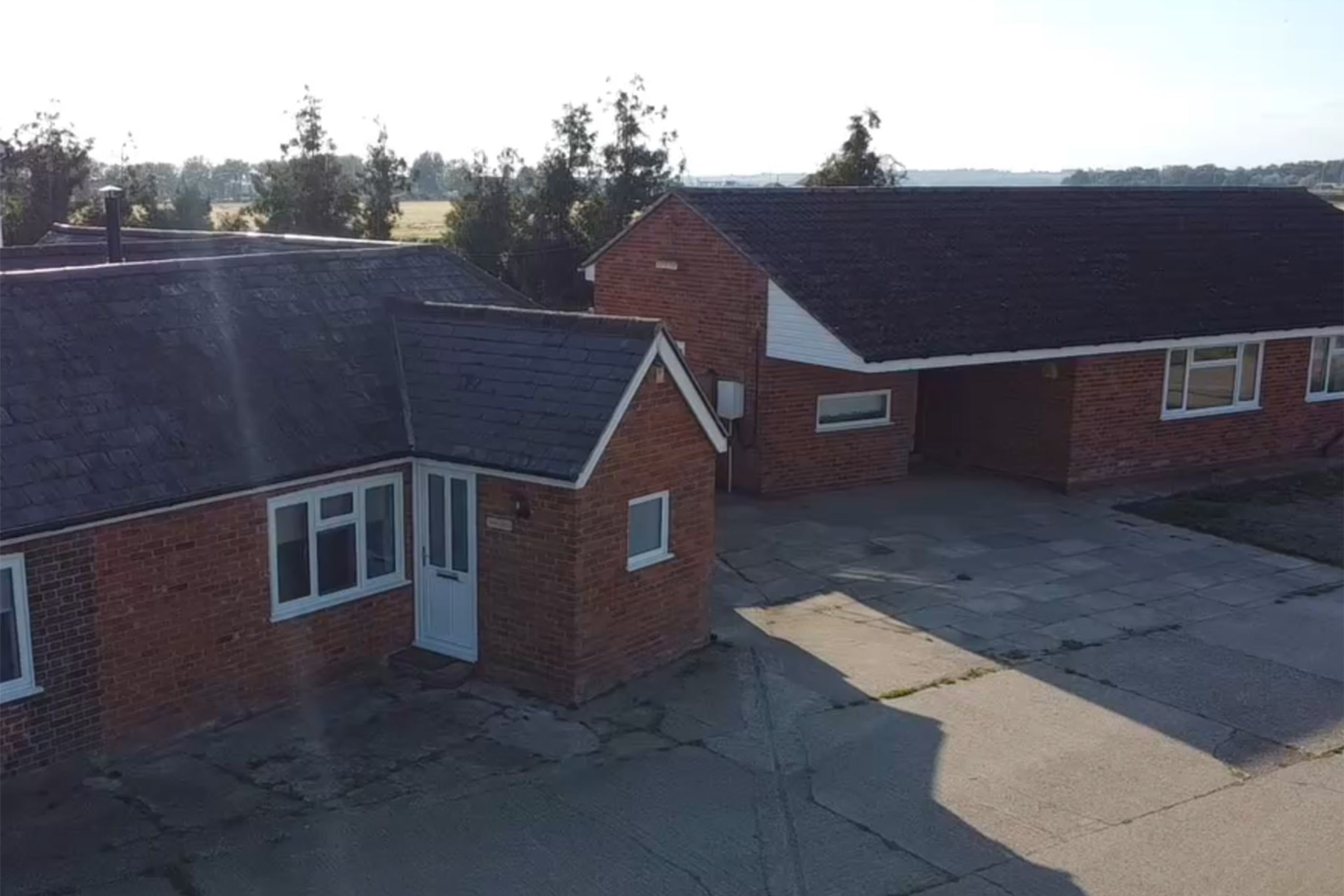 Een woongebied met bakstenen huizen, een geplaveid binnenterrein en een heldere lucht.