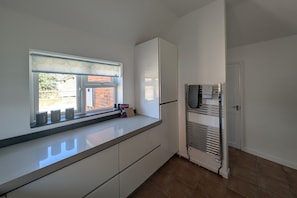A kitchen with a window, white cabinets, a built-in oven, and a towel rack.