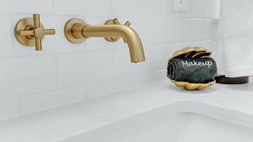 A bathroom with a gold faucet, a towel rack, and a towel with 'Makeup' written on it.