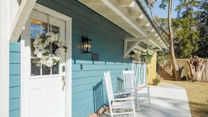 A house with a white door, a porch with white rocking chairs, and a blue exterior.