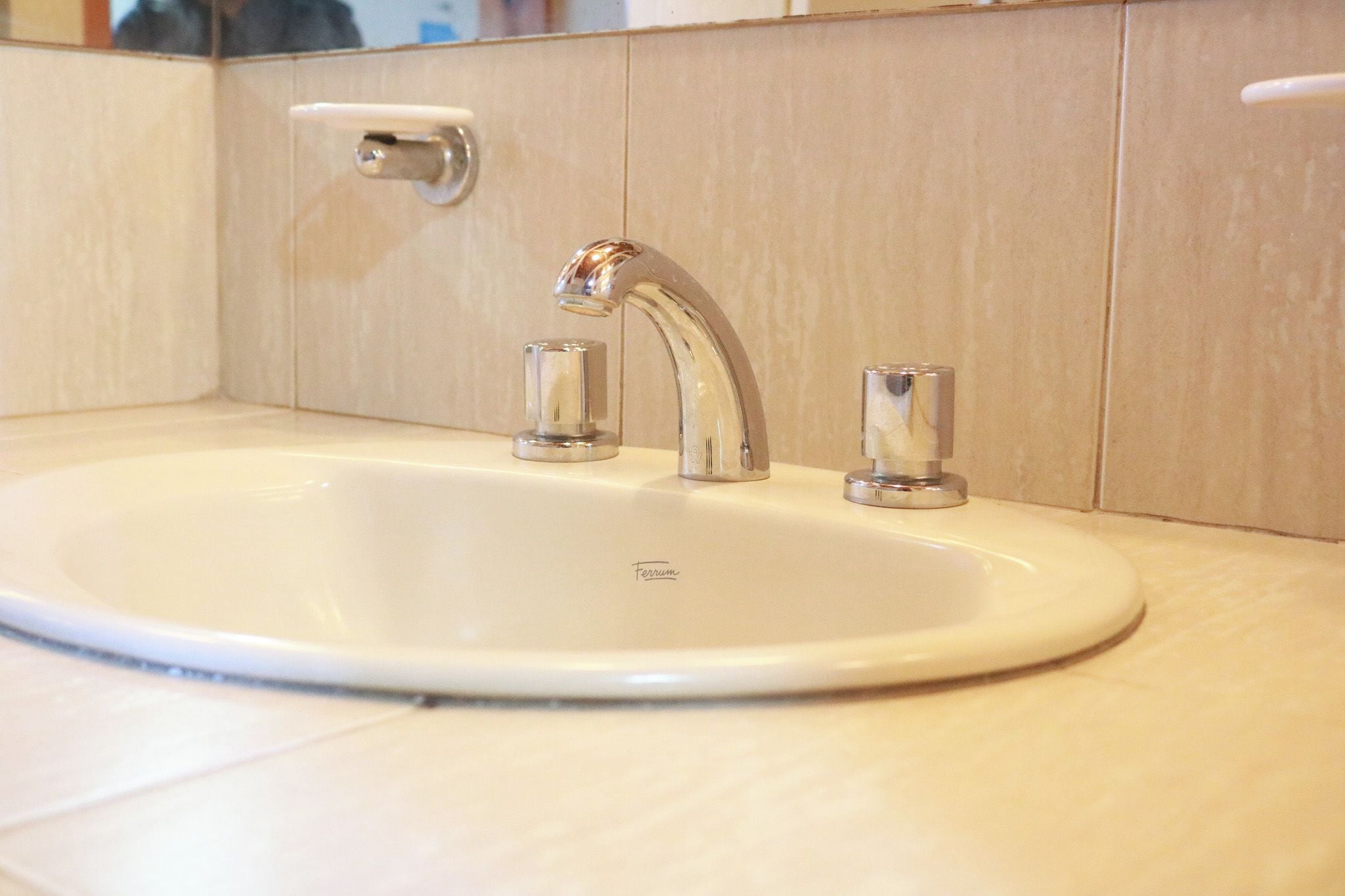 A bathroom sink with a single faucet and a soap dispenser.