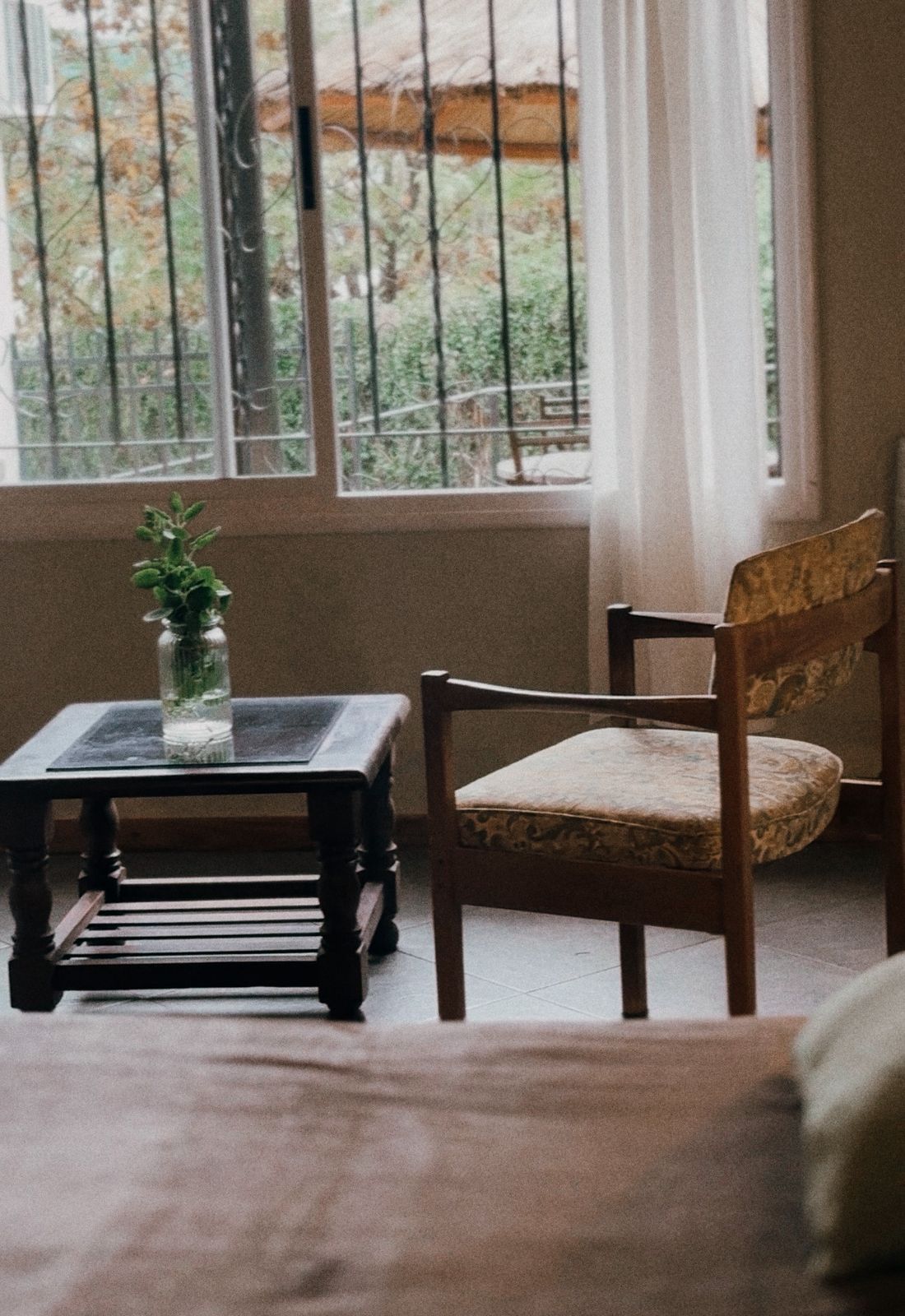 Una habitación con una silla de madera y una pequeña mesa con una planta.