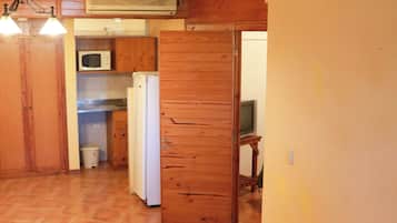 Un intérieur en bois comprenant un coin cuisine équipé d’un four à micro-ondes, d’un réfrigérateur et d’un téléviseur posé sur un meuble.