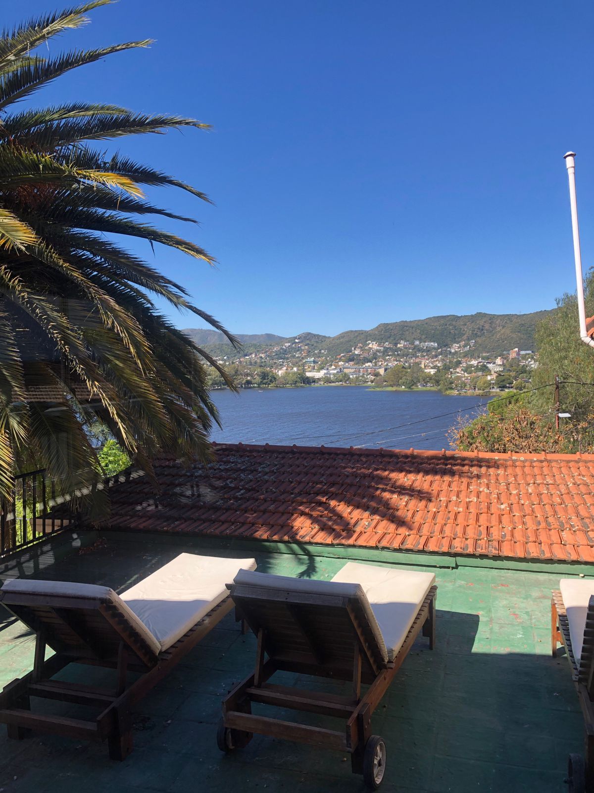 Una terraza con sillones de descanso, vistas a un lago y un pueblo lejano.