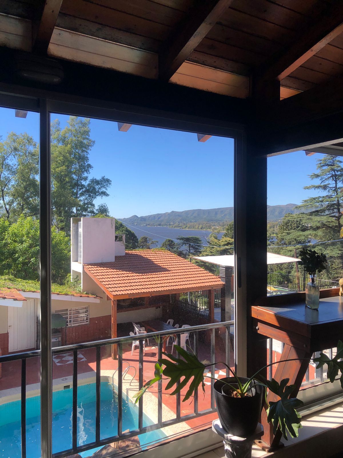 Un balcón con vista a una piscina y montañas al fondo.