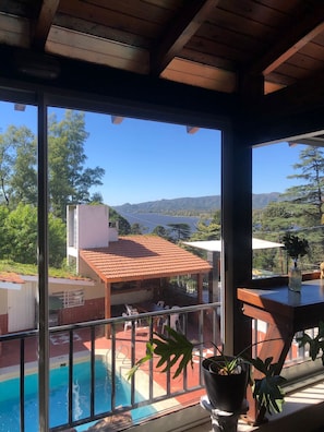 Un balcón con vista a una piscina y montañas al fondo.
