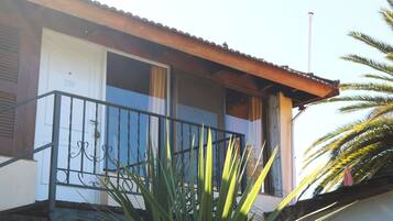 A residential building with a balcony, a door marked with the number 200, and a palm tree in the foreground.
