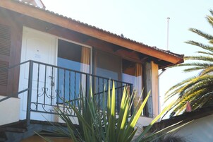 Un edificio residencial con un balcón, una puerta marcada con el número 200 y una palmera en primer plano.