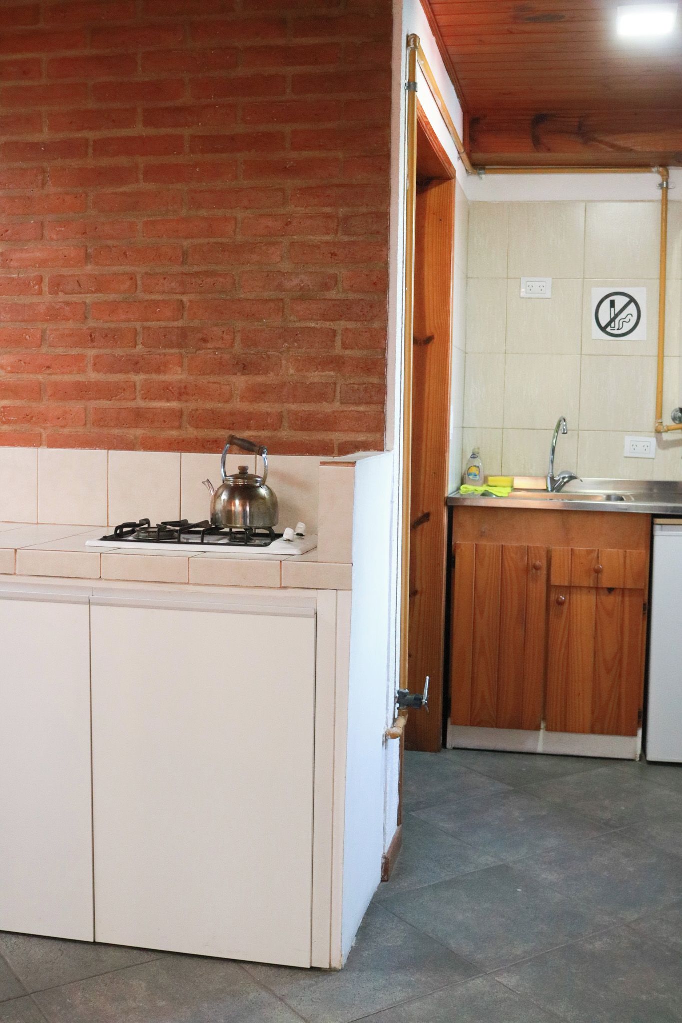 A kitchen with a gas stove, a kettle, and a sink.