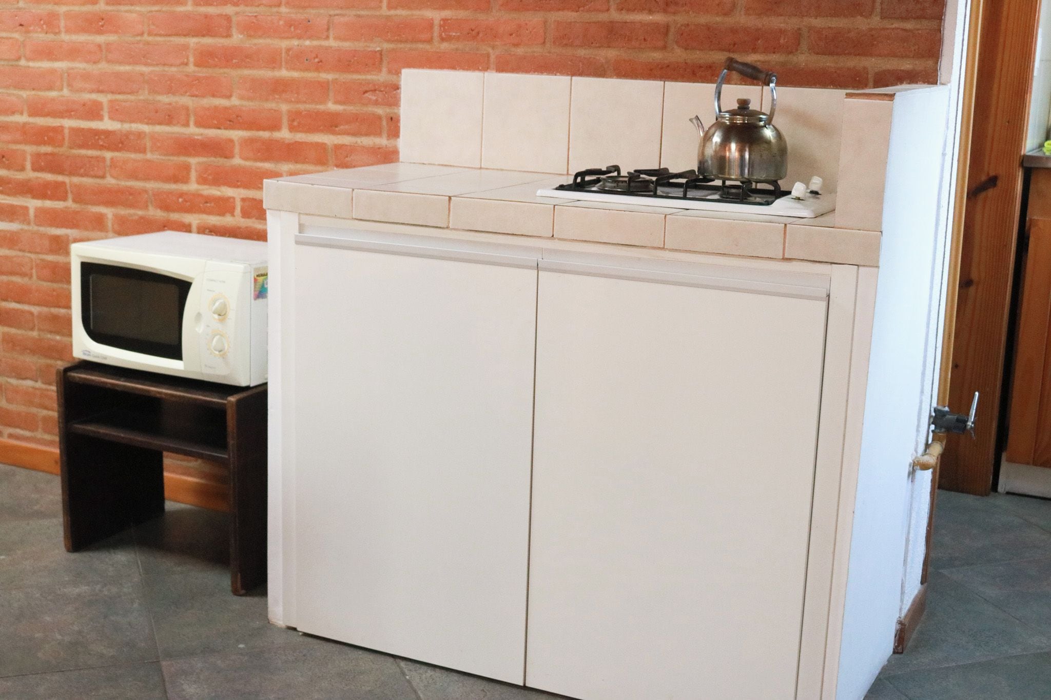 Una cocina compacta con estufa a gas, hervidor y microondas.