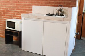 A compact kitchen with a gas stove, kettle, and microwave.