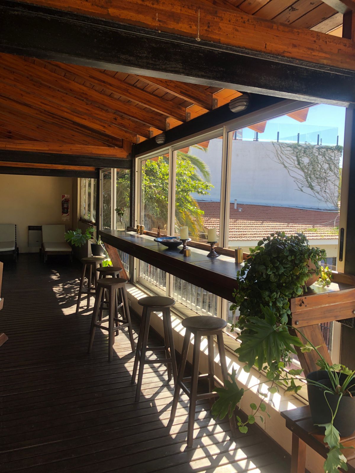 A wooden deck with a bar area, stools, and potted plants.