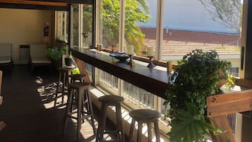 A wooden deck with a bar area, stools, and potted plants.