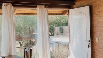 Una stanza con soffitto in legno, un letto, un tavolo con una sedia e vista su un balcone esterno.