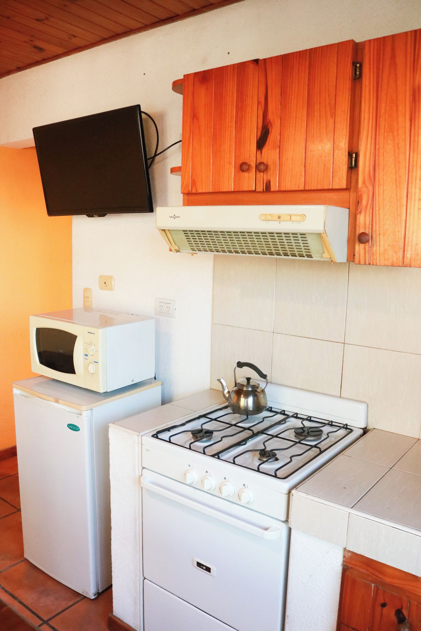 Una cocina compacta equipada con estufa a gas, microondas y refrigerador.
