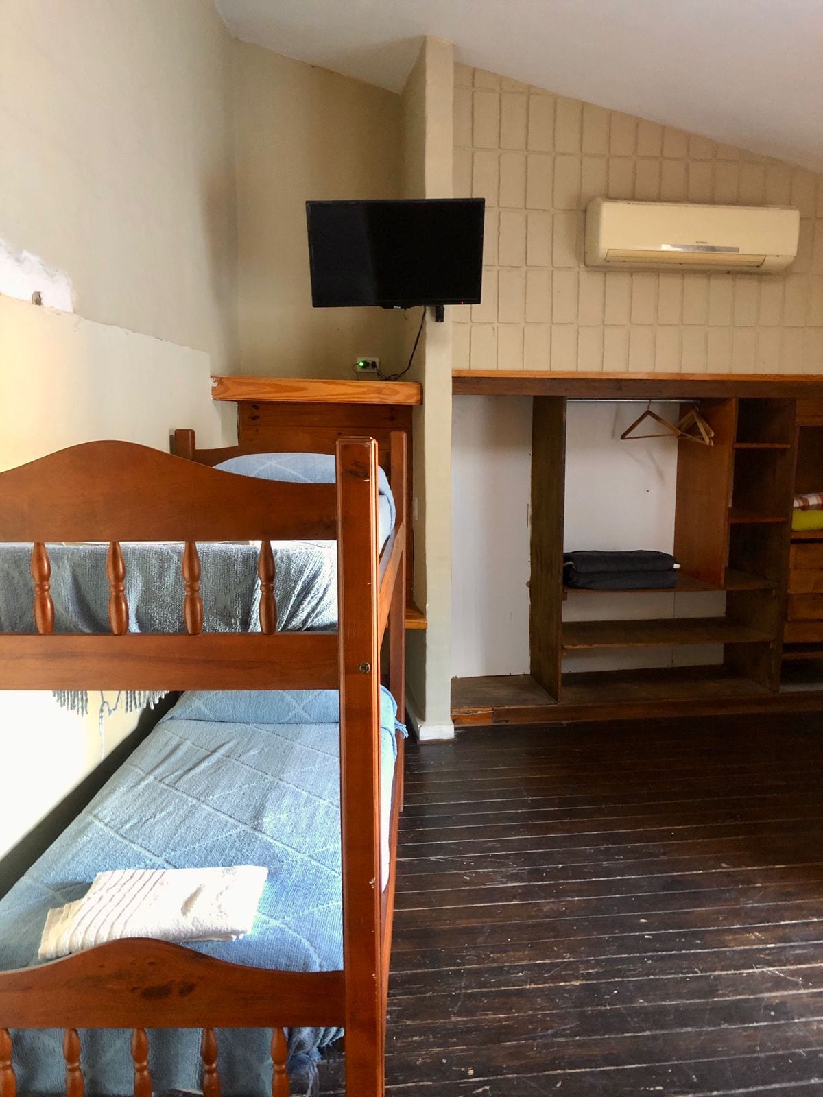 Una habitación con literas, un escritorio con silla, un televisor y un equipo de aire acondicionado.
