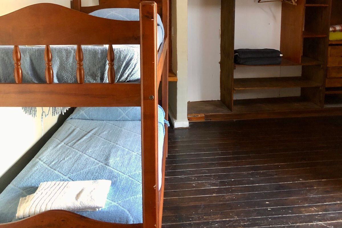 Een kamer met een stapelbed, een bureau met stoel, een televisie en een airconditioning.