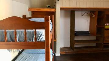 Una habitación con literas, un escritorio con silla, un televisor y un equipo de aire acondicionado.