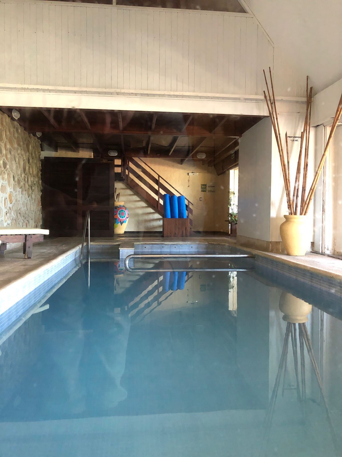 Una piscina con cubierta de madera, una escalera y una pared con textura.