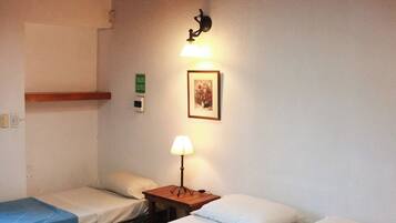 A room with two beds, a wall-mounted light, and a framed picture.