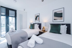 Habitació d'hotel moderna amb dos llits, una finestra gran i obra d'art a les parets.