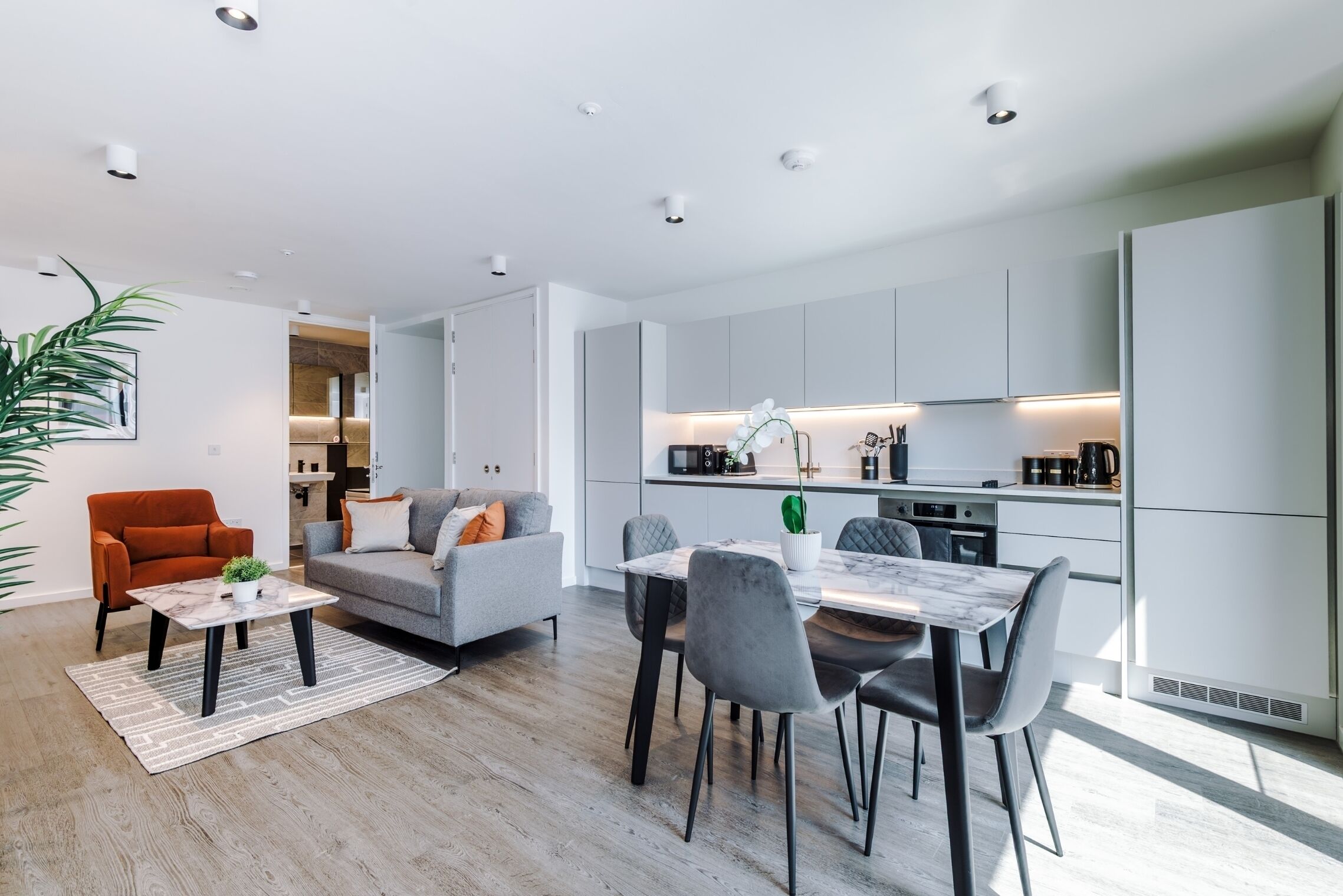 A modern living space with a dining area, kitchen, and a sofa.