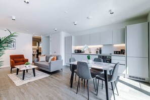 Ein modernes Wohnzimmer mit Sofa, Couchtisch und Essbereich mit Stühlen.