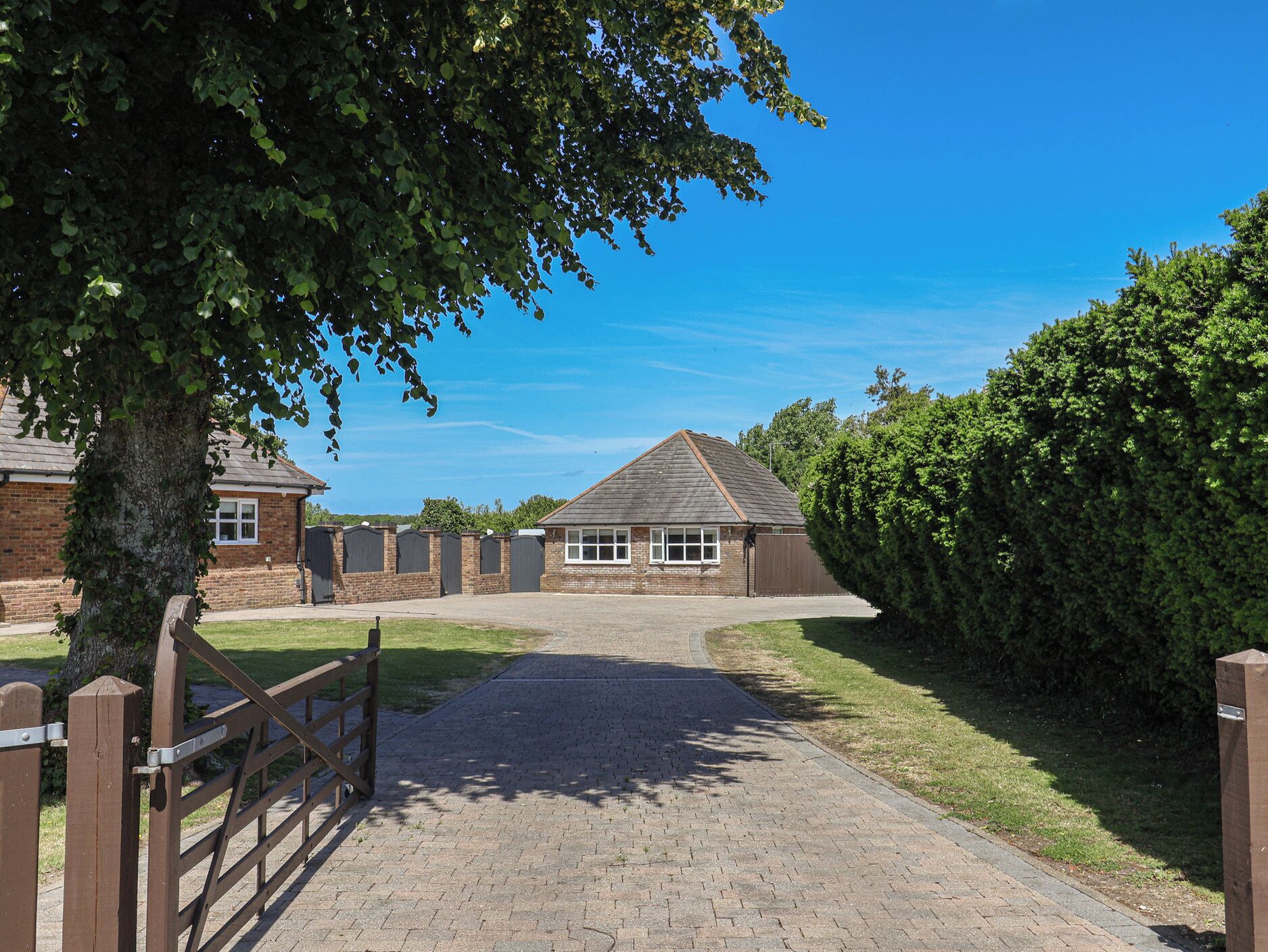 A brick building with a paved driveway leading to a gated entrance.