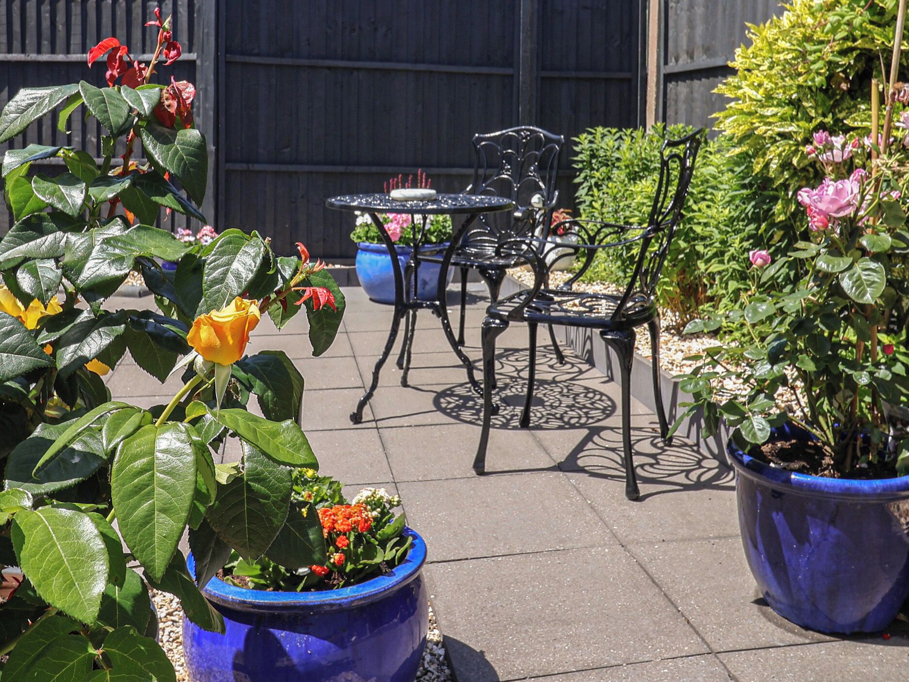 Eine Terrasse mit Sitzgelegenheiten im Freien, Blumentöpfen und einem Garten.