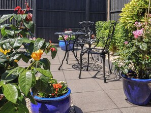 Eine Terrasse mit Sitzgelegenheiten im Freien, Blumentöpfen und einem Garten.