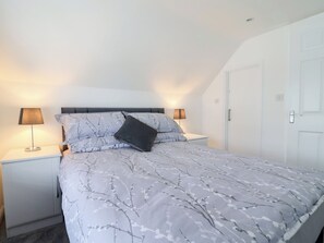 A bedroom with a bed, two bedside lamps, a nightstand, and a door. - Frome View (Wareham)