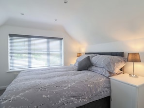 Ein Schlafzimmer mit einem Bett, zwei Nachttischlampen, einem Fenster mit Jalousien und einer Deckenleuchte.