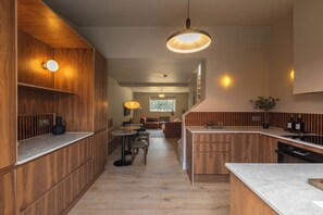 A modern kitchen with wooden cabinetry, a marble countertop, and pendant lighting. - Hertfordshire Cottage, Designer, with Barn Suite (Wandon Green)