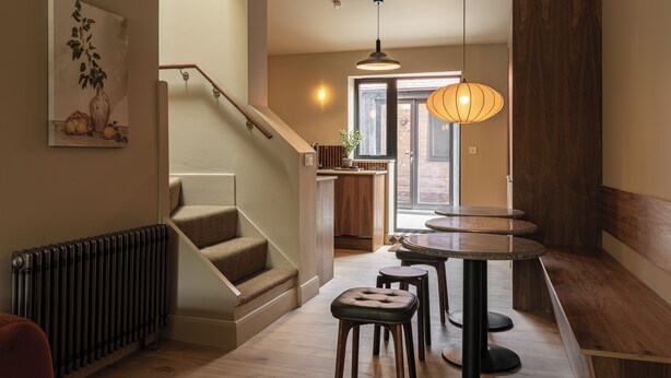 A staircase leading to a kitchen area with a dining table and stools, a radiator, and a hanging light fixture. - Hertfordshire Cottage, Designer, with Barn Suite (Wandon Green)
