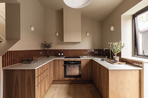 Une cuisine moderne avec des meubles en bois, un four encastré et une fenêtre.