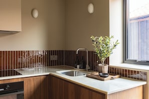 A kitchen with a wooden countertop, a sink, a stove, and a window with a view.