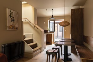Un escalier menant à un espace cuisine équipé d’une table à manger et de tabourets.