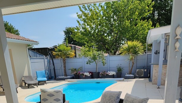 A covered outdoor seating area with wicker furniture, a pool, and potted plants. - House with a Pool: The Charm of the Pool in Gujan-Mestras (Gujan-Mestras)