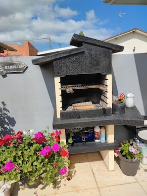A barbecue grill attached to a wall, with a sign indicating its use. - House with a Pool: The Charm of the Pool in Gujan-Mestras (Gujan-Mestras)
