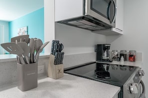 Une cuisine moderne dotée d’une plaque de cuisson à induction noire, d’appareils électroménagers en acier inoxydable et d’une machine à café.