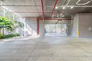 Un parking souterrain avec des planchers en béton et des tuyaux rouges au plafond.
