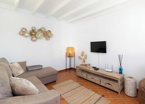 Ein Wohnzimmer mit einer Couch, einem Fernseher, einer Lampe und Dekoration an der Wand.