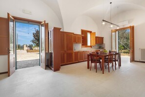 A spacious kitchen with wooden cabinets, a dining table, and chairs. - Villa Demetra by BarbarHouse (Cutrofiano)
