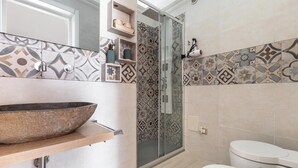 Une salle de bain avec un lavabo sur colonne, une douche à parois de verre et des toilettes.