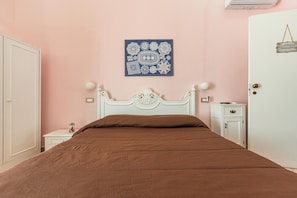 A bedroom with a bed, a nightstand, a dresser, a wall-mounted artwork, and a door with a sign. - Nonna Tetta - Camera Queen by BarbarHouse (Novoli)